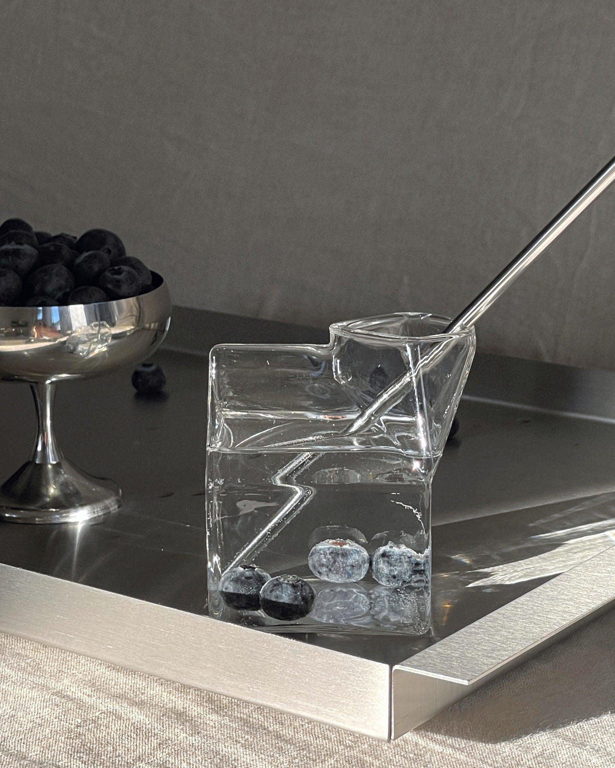 edelstahl tablett mit milchkarton glas und blaubeeren im morgenlicht