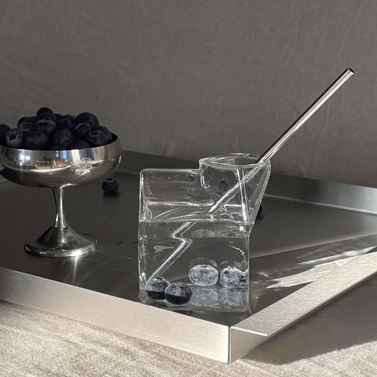 edelstahl tablett mit milchkarton glas und blaubeeren im morgenlicht