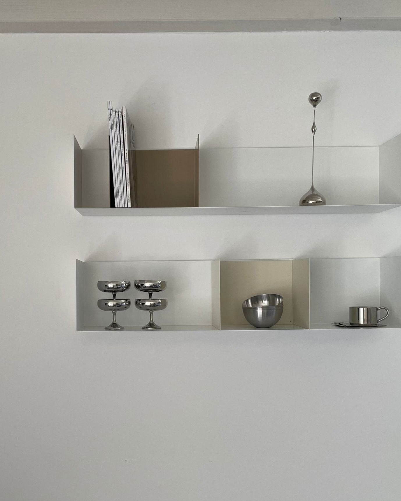 Modernes Wandregal in Weiß mit Buchstützen in Cremeweiß und Graubeige, stilvoll dekoriert