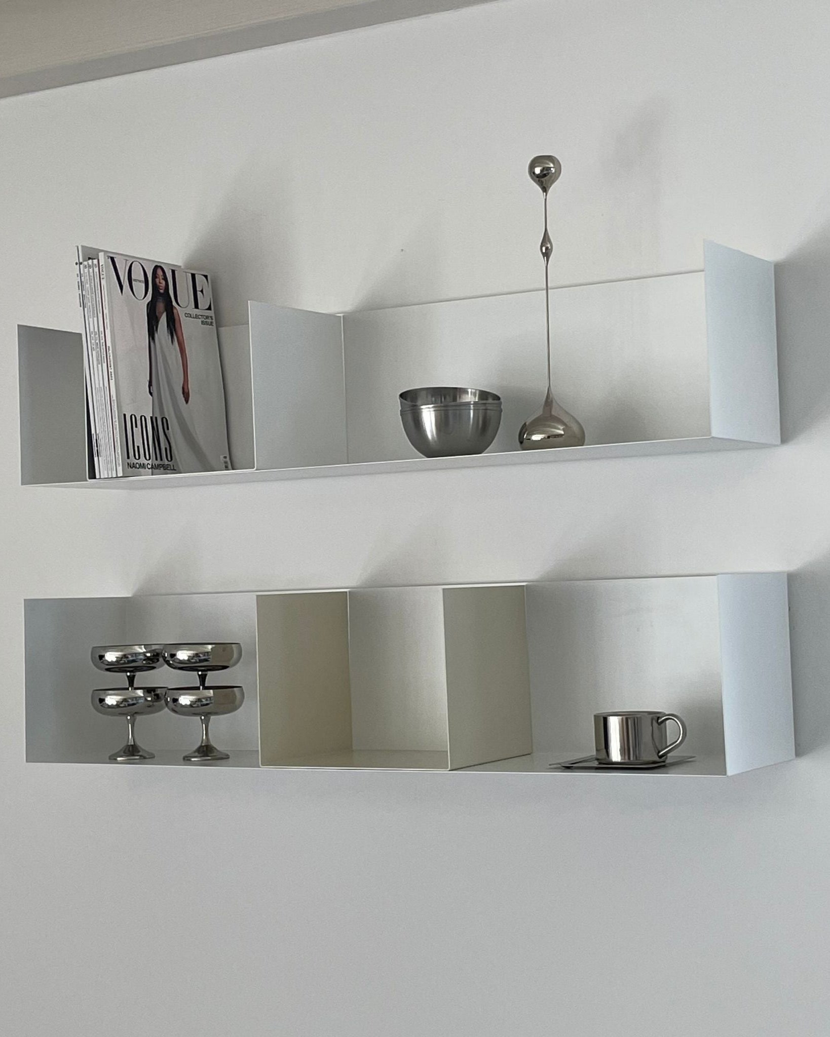 Modernes weißes Wandregal mit Buchstützen in Cremeweiß, dekoriert mit Magazinen und Edelstahl-Accessoires