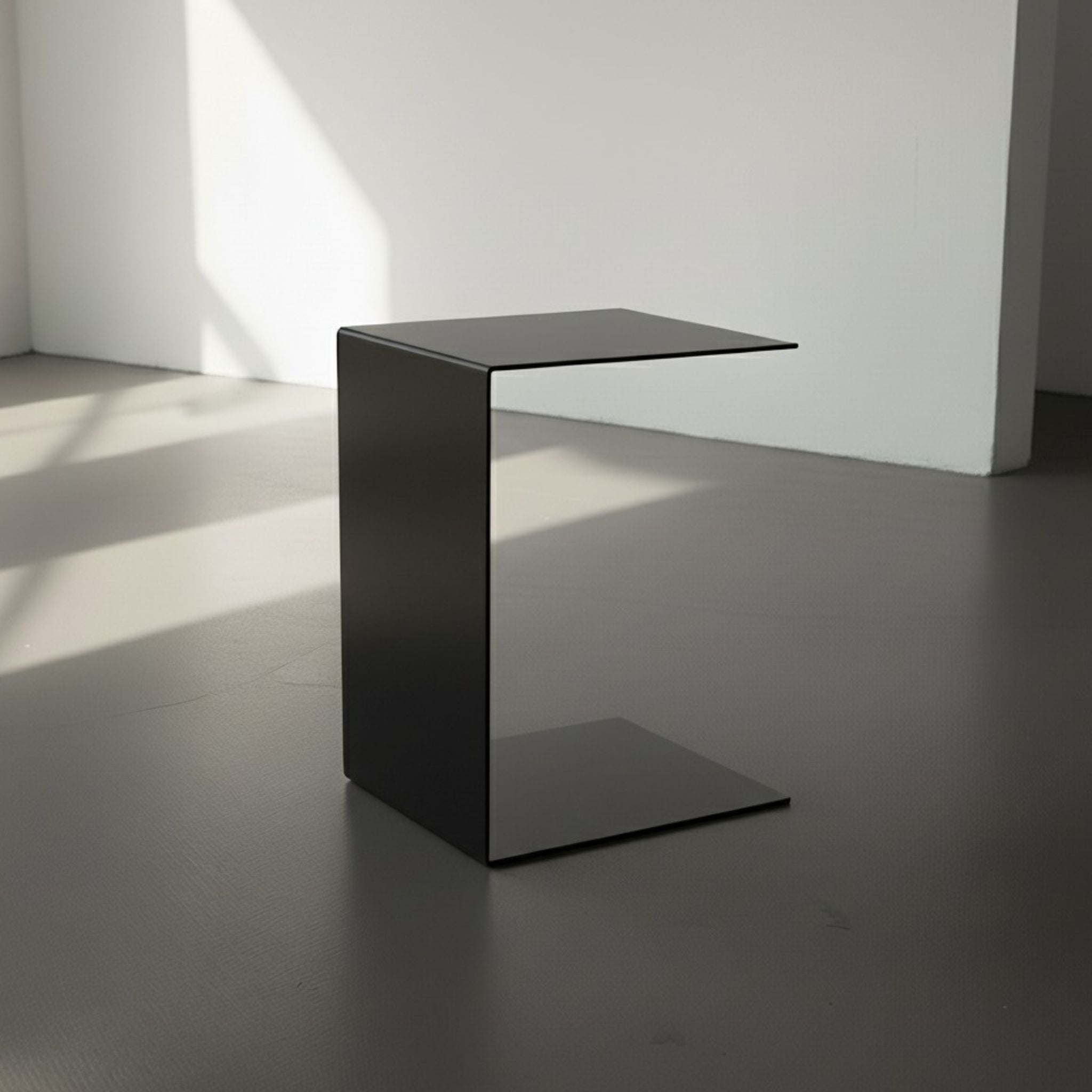 BIG C in schwarz auf grauen Betonboden vor weißer Wand und Lichtspiel