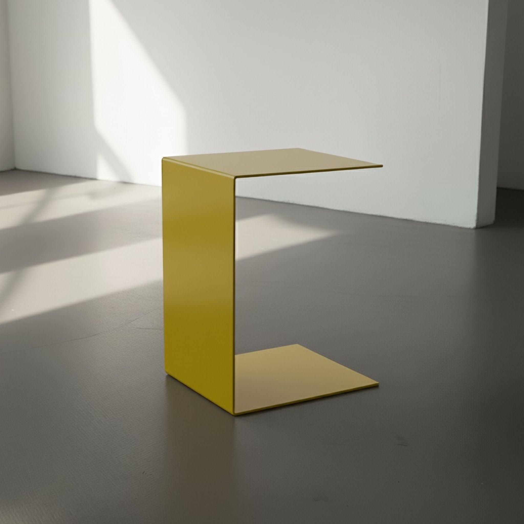 BIG C in schwefelgelb auf grauen Betonboden vor weißer Wand und Lichtspiel