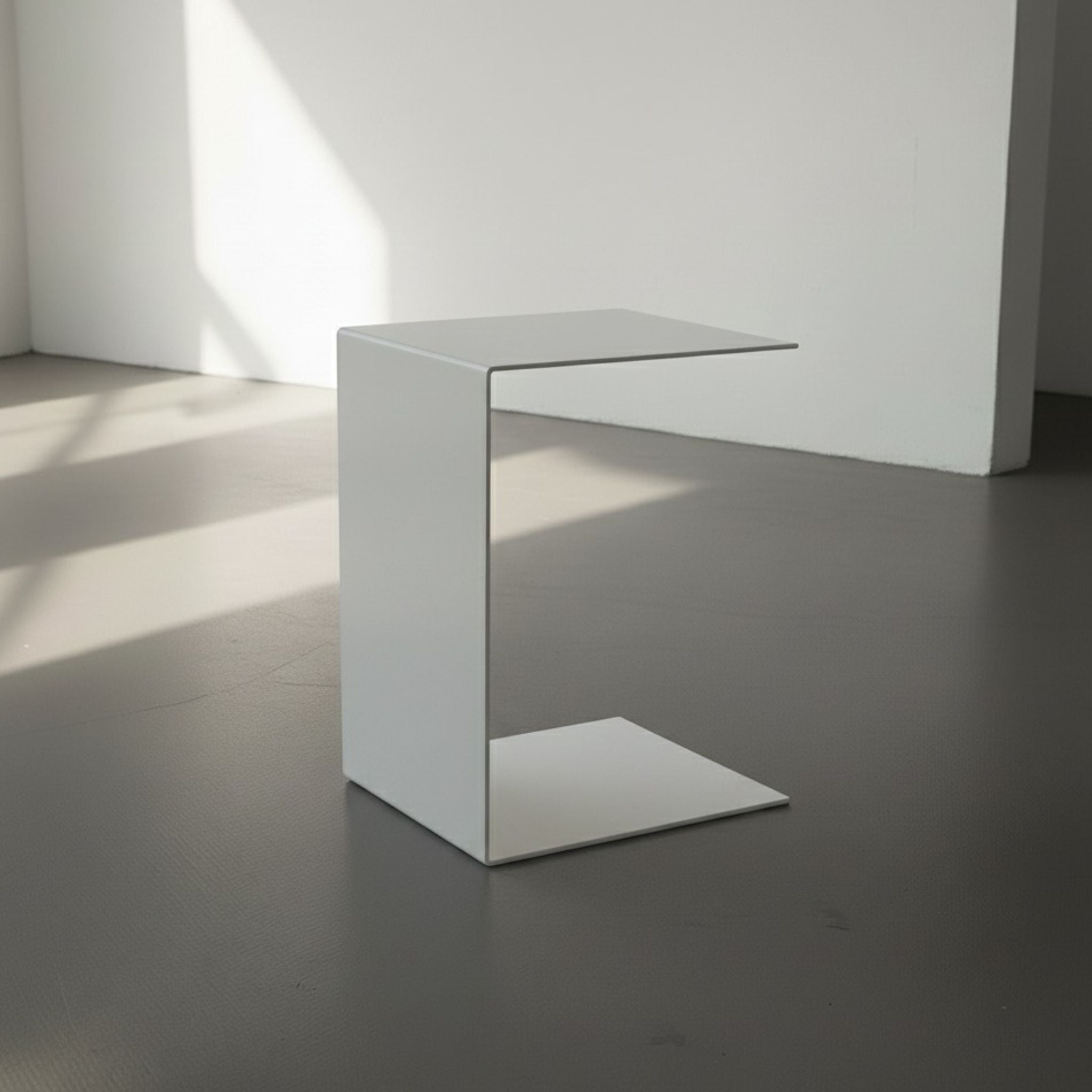 BIG C in weiß auf grauen Betonboden vor weißer Wand und Lichtspiel