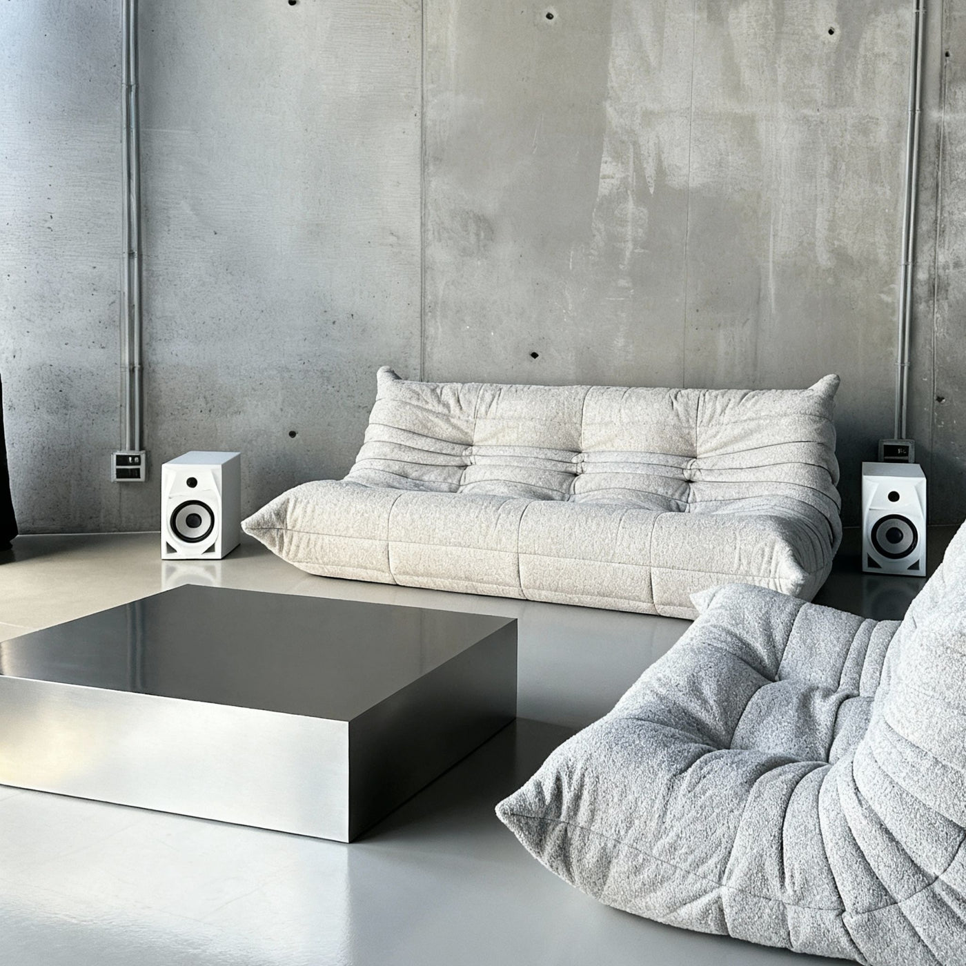 Couchtisch Brushed Q aus gebürstetem Edelstahl vor Betonwand