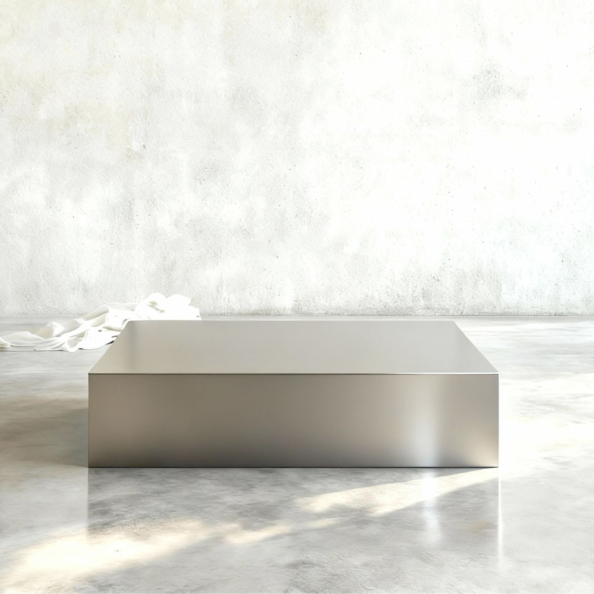 Brushed Q Couchtisch aus gebürstetem Edelstahl in reduzierter Frontansicht auf hellem Betonboden