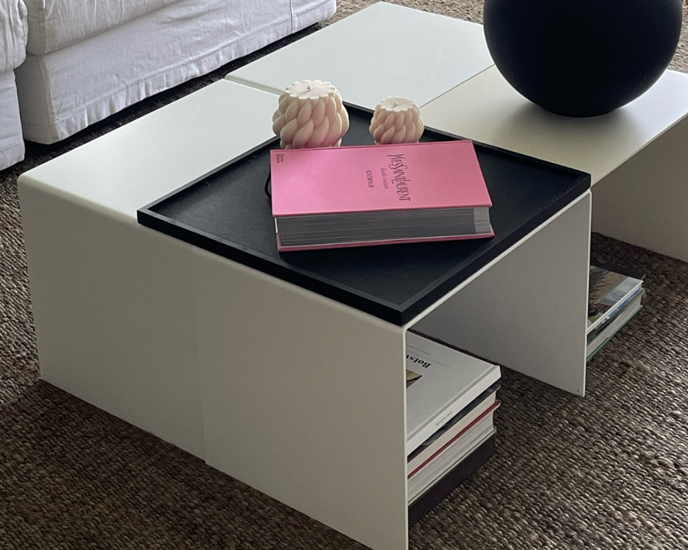 Moderner weißer Couchtisch mit integriertem Regal, dekoriert mit schwarzer Vase, Designbuch und Kerzen in einem stilvollen Wohnzimmer