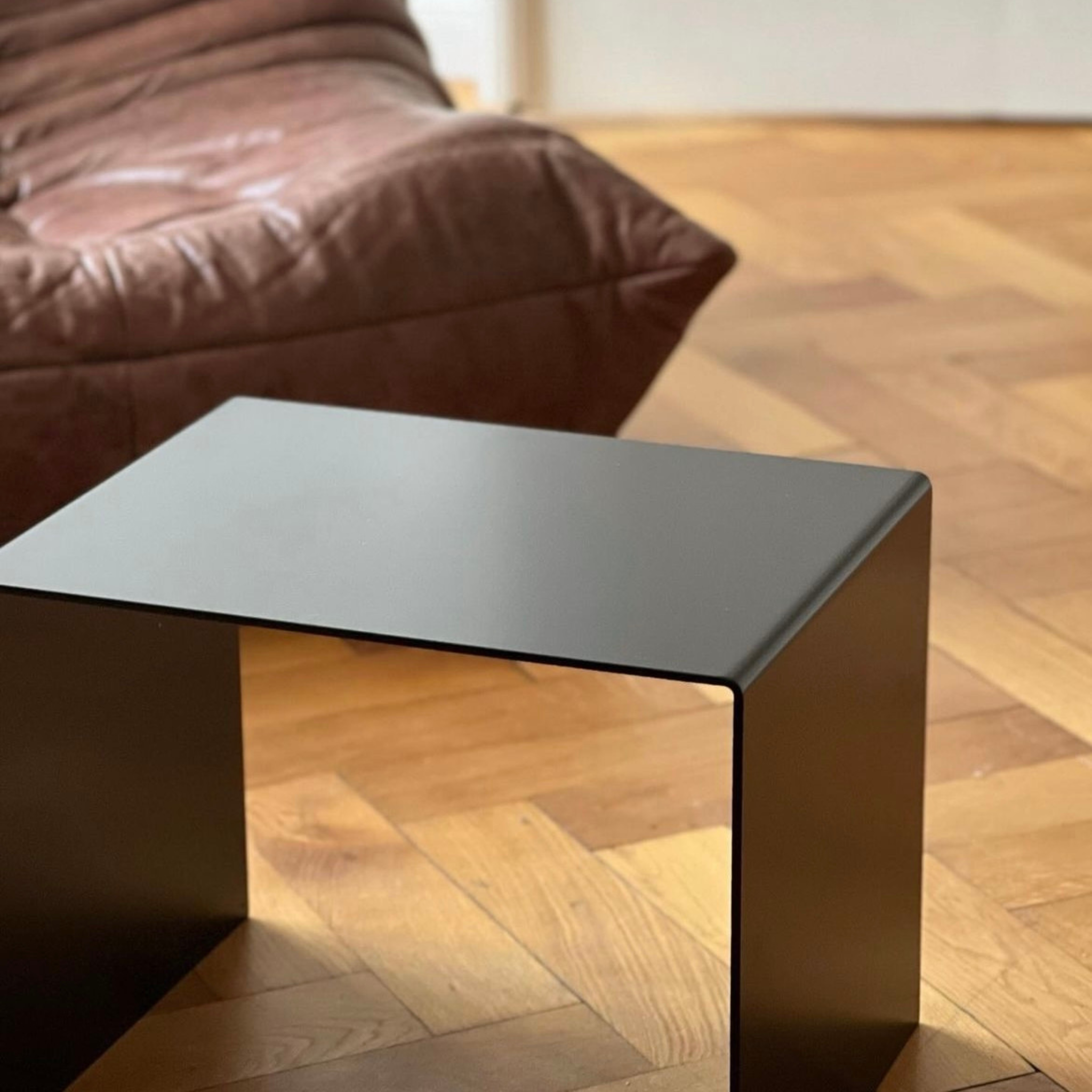 Schwarzer minimalistischer Beistelltisch aus Metall auf Parkettboden, modernes Wohnzimmerdesign