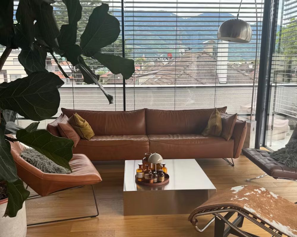 Brushed Q Couchtisch aus gebürstetem Edelstahl im Wohnzimmer einer Kundin mit Ledersofa und Designklassikern