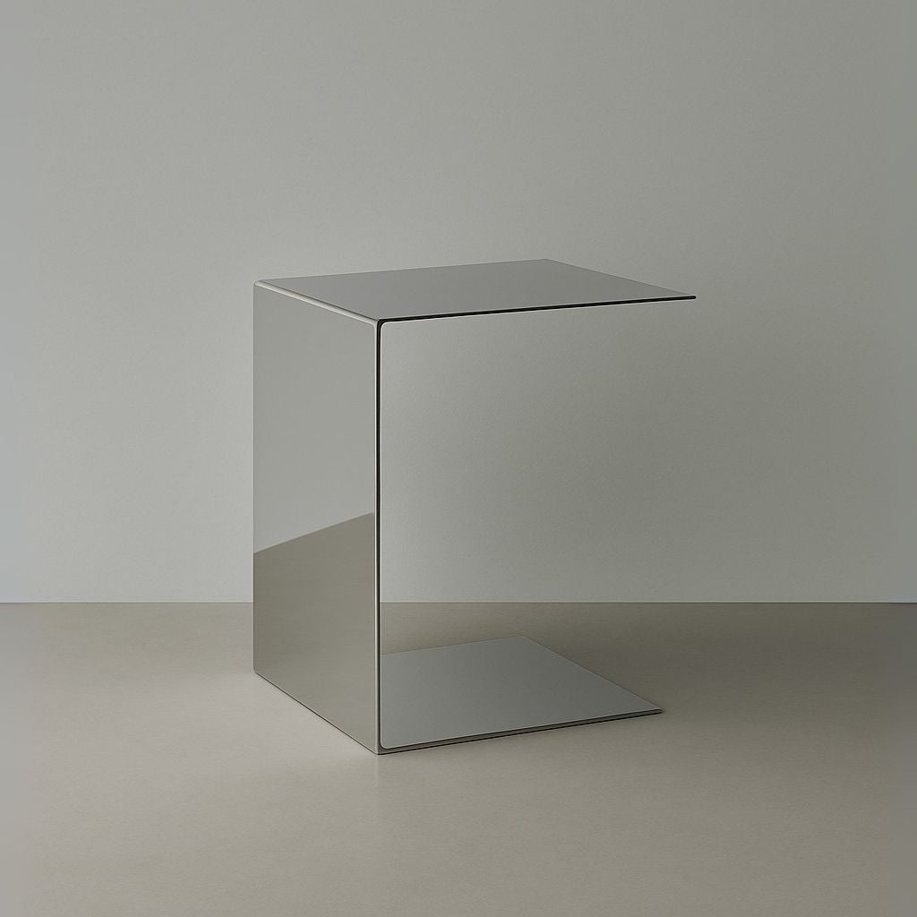 Beistelltisch Mirror C aus spiegelpoliertem Edelstahl im minimalistischen C-Design auf hellem Boden vor grauer Wand