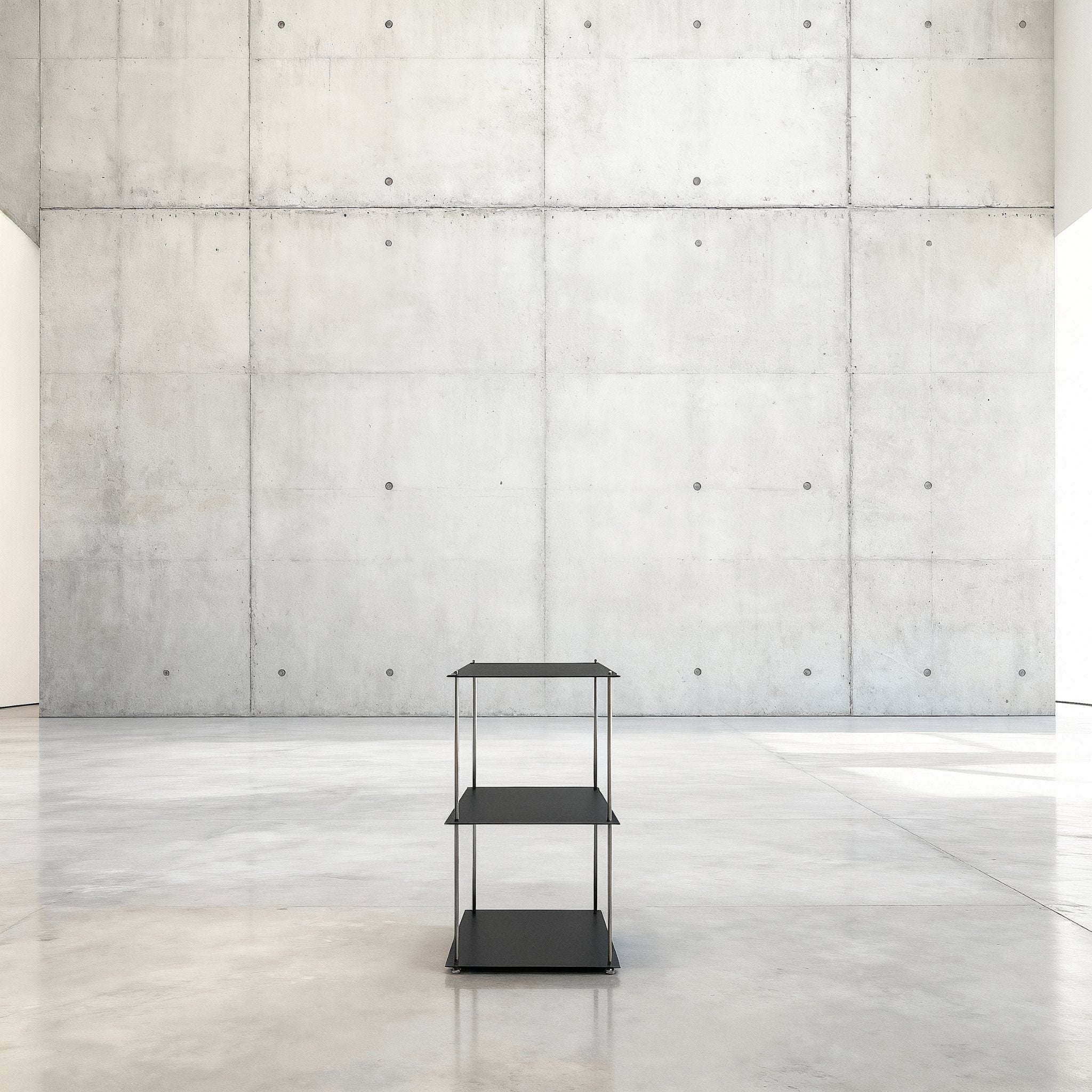 Modulum mit 3 Fachböden in schwarz ultramatt auf grauen Betonboden vor grauer Betonwand mit Löchern