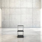 Modulum mit 3 Fachböden in schwarz ultramatt auf grauen Betonboden vor grauer Betonwand mit Löchern