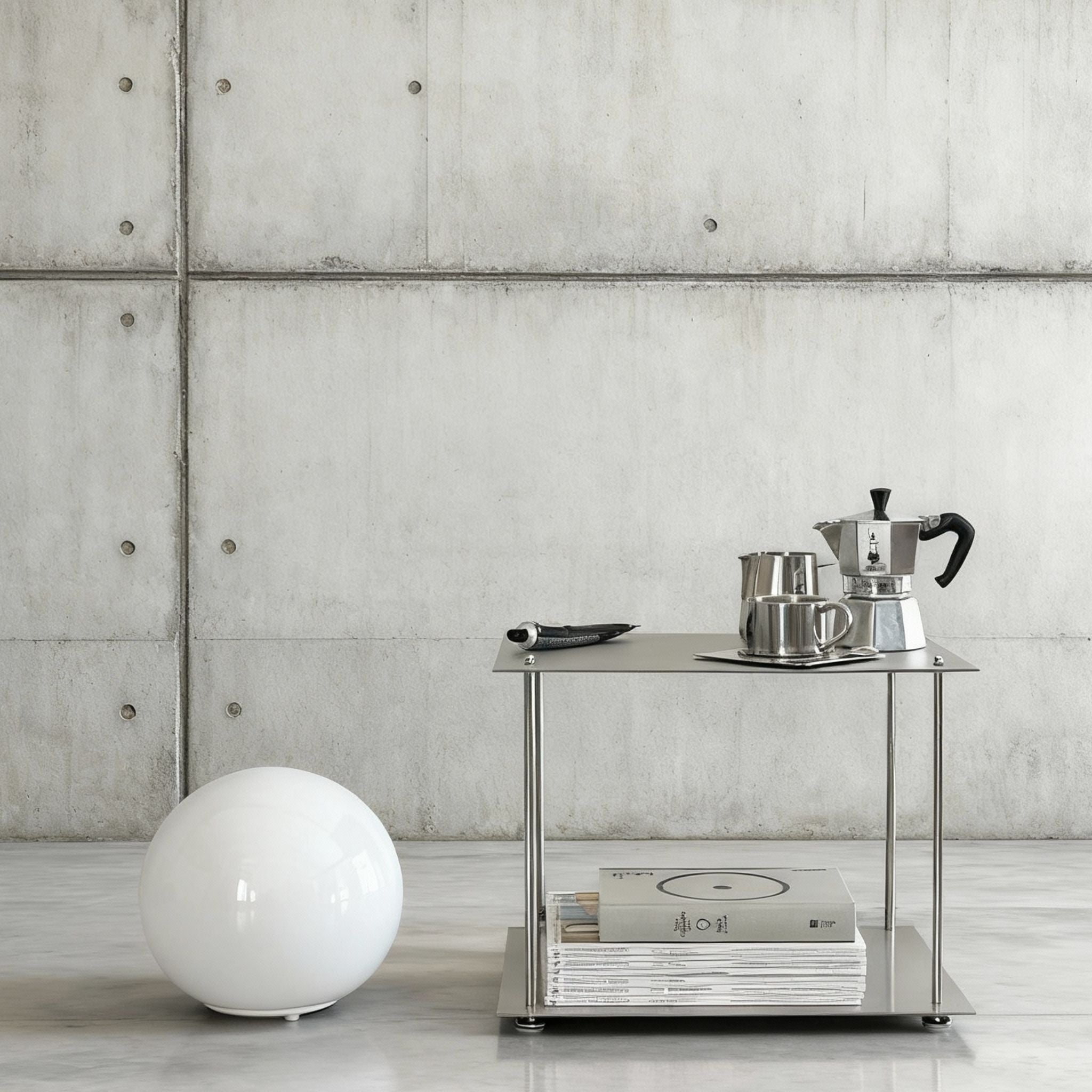 Modulum Regalsystem aus Edelstahl mit Kaffeeset und Magazinen in modernem Betonraum mit minimalistischer Kugellampe