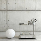 Modulum Regalsystem aus Edelstahl mit Kaffeeset und Magazinen in modernem Betonraum mit minimalistischer Kugellampe