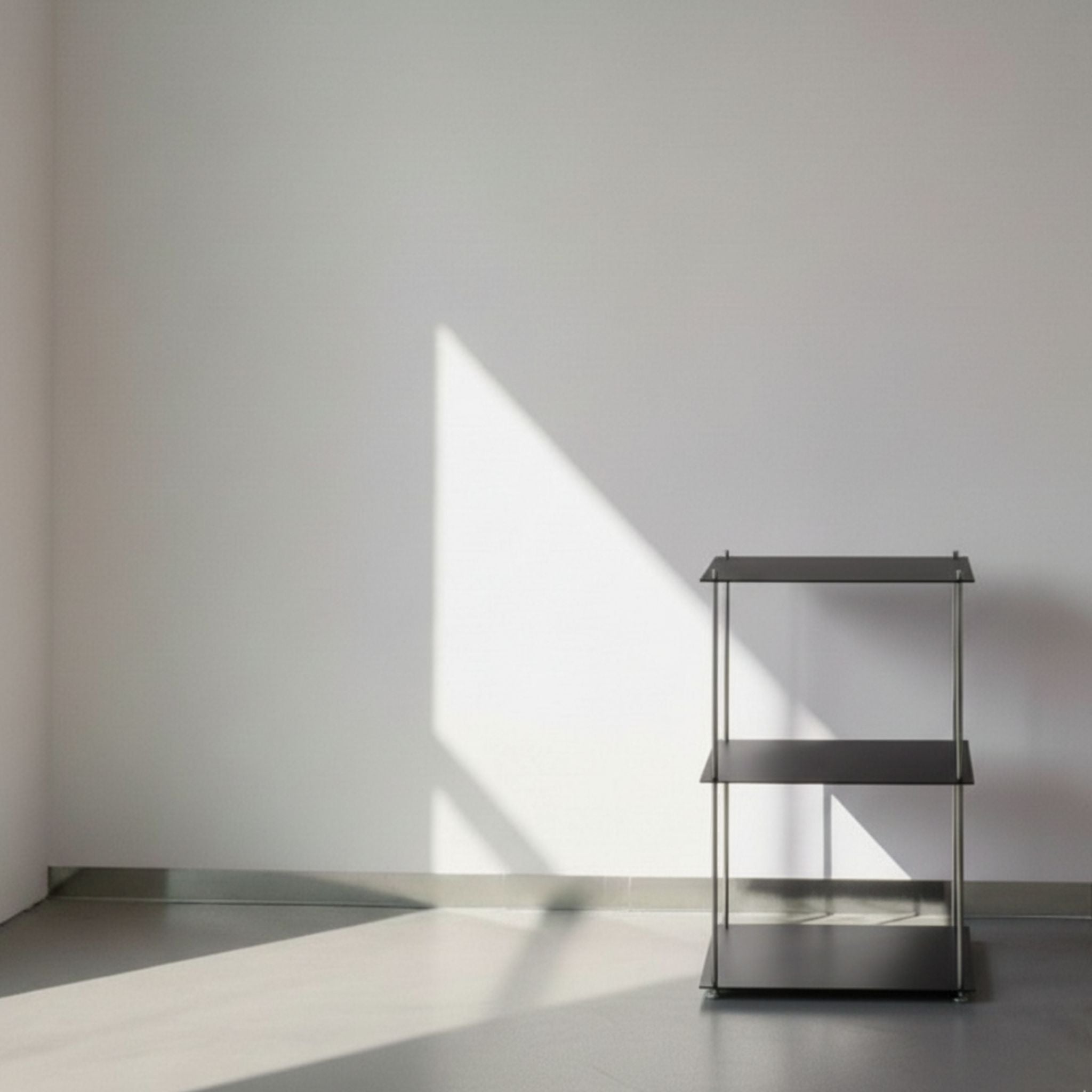 Modulum in schwarz ultramatt mit 3 Fachböden auf grauen Betonboden vor weißer Wand und Lichtspiel