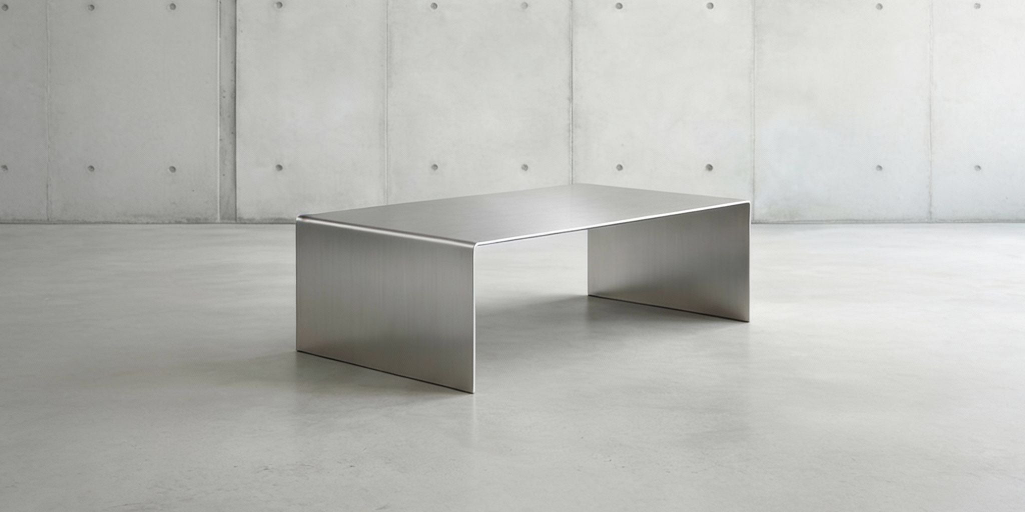 Starsteitenbanner 2028x1024 Brushed C Long Couchtisch aus gebürstetem Edelstahl in minimalistischer Studioinszenierung vor Betonwand