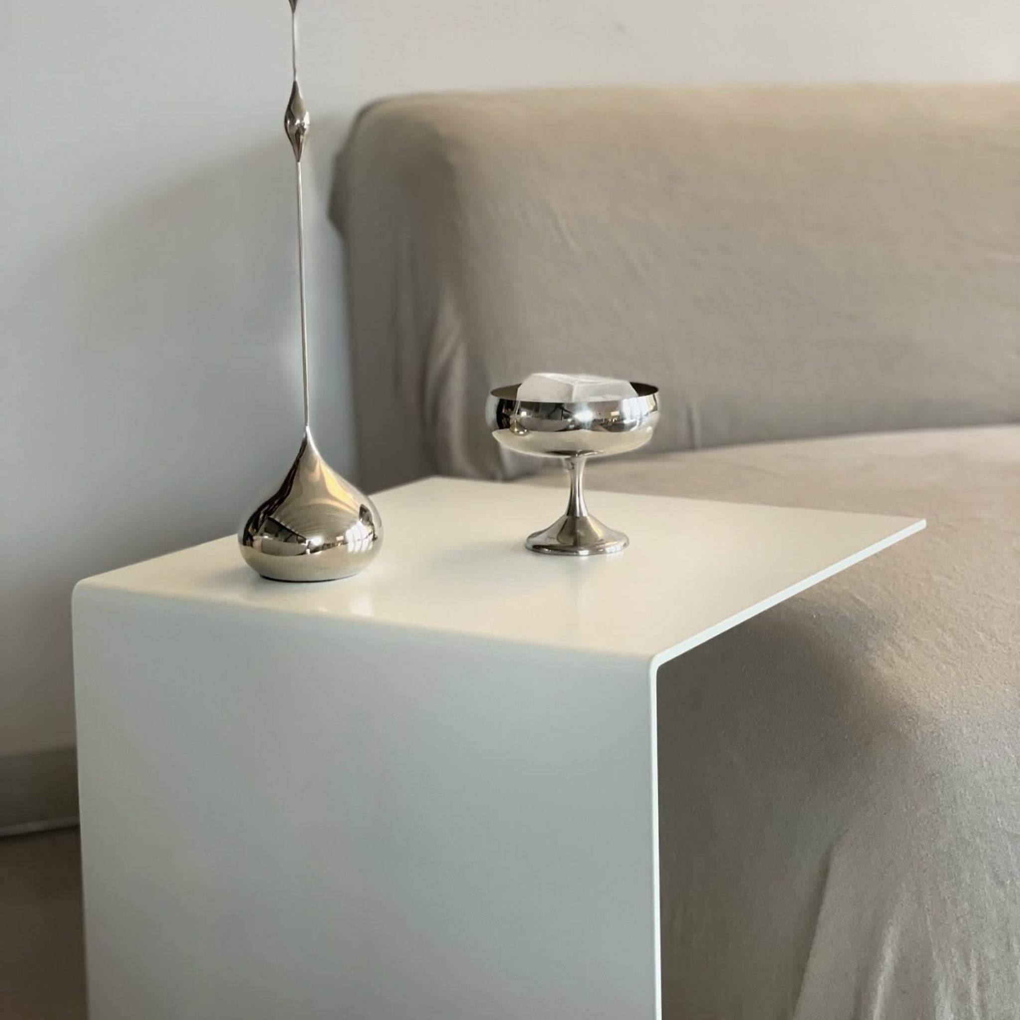 Minimalistischer Beistelltisch in Weiß mit Edelstahl-Dekoration am Sofa