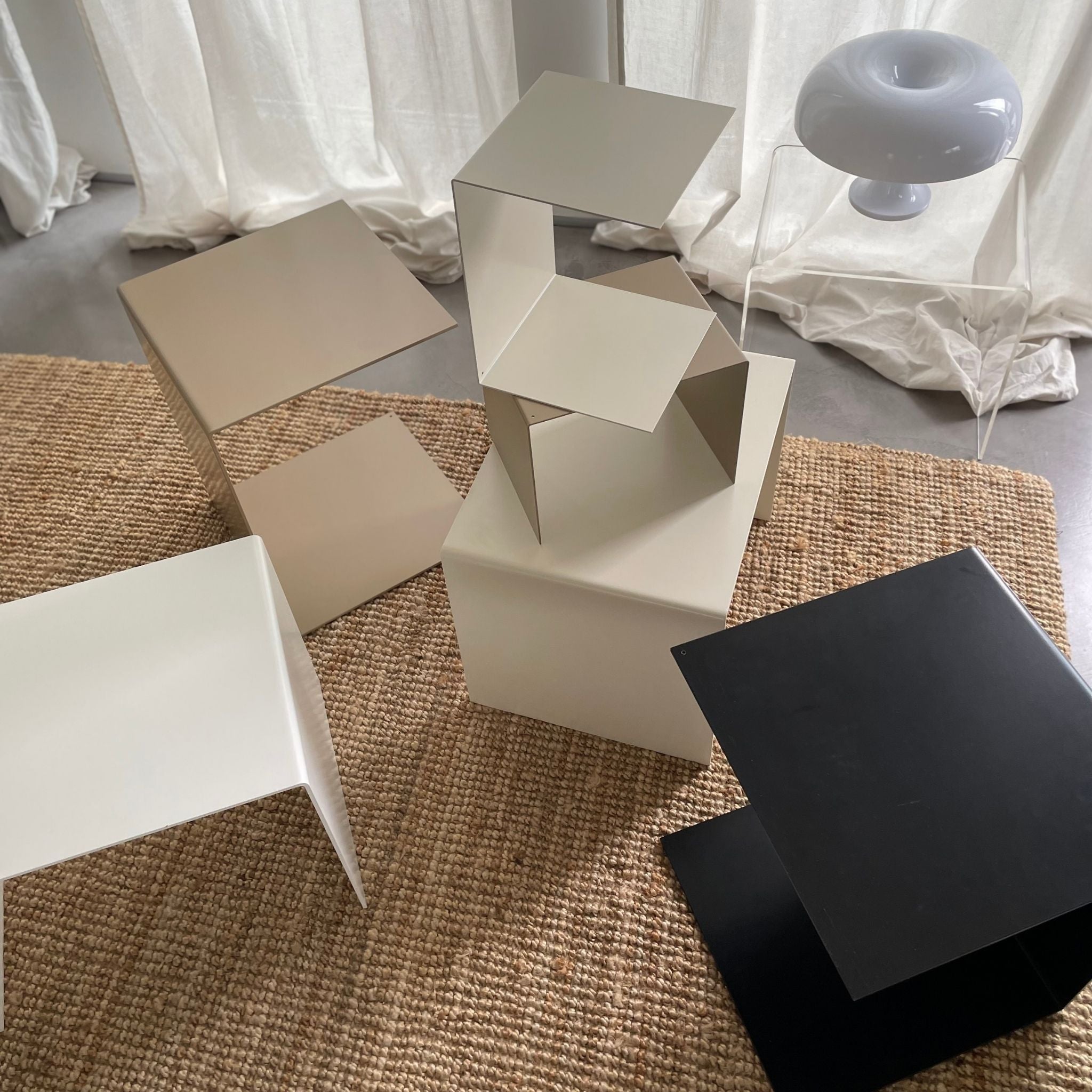 Moderne Beistelltische und Couchtische in verschiedenen Farben auf Naturteppich mit minimalistischer Deko