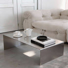 Brushed C Long Couchtisch aus gebürstetem Edelstahl mit Büchern und Keramik im minimalistischen Wohnzimmer vor Sofa