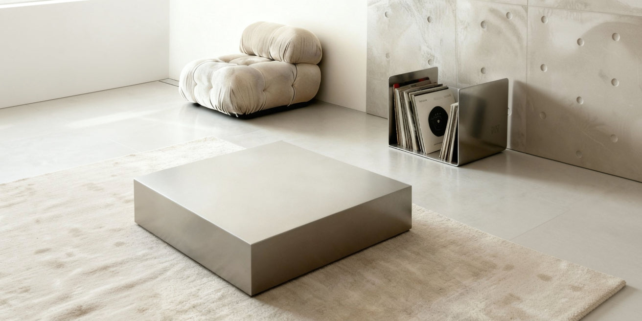 Minimalistischer Couchtisch aus gebürstetem Edelstahl auf hellem Teppich in modernem Wohnraum