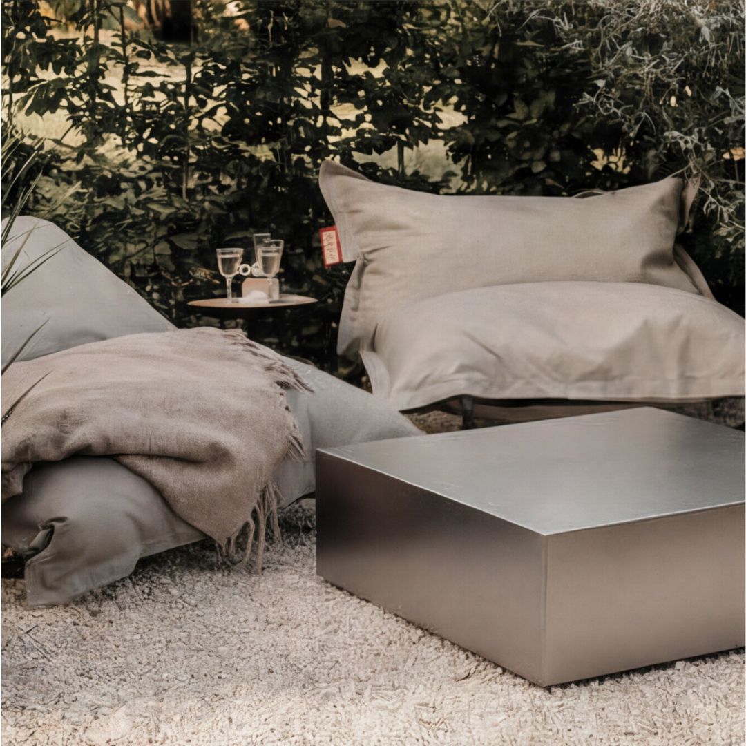 Brushed Q Couchtisch aus gebürstetem Edelstahl im Outdoor Lounge Setting mit Sitzkissen und Decke