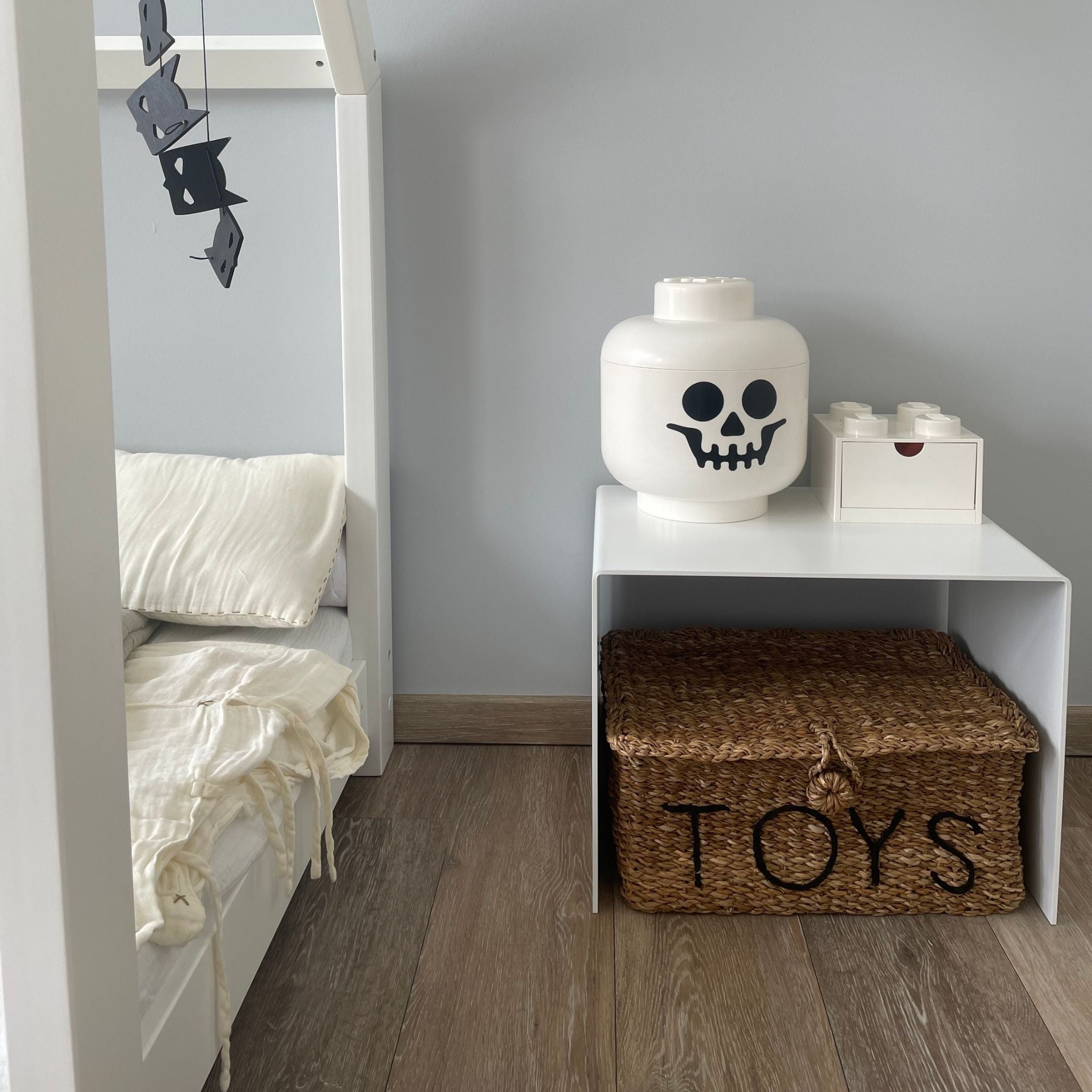 Weißer Couchtisch als Ablage im Kinderzimmer mit Spielzeugkiste und Dekoration auf Holzboden