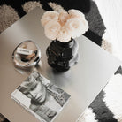 Moderner Couchtisch aus Edelstahl mit Vase, Duftkerze und Magazin auf Teppich