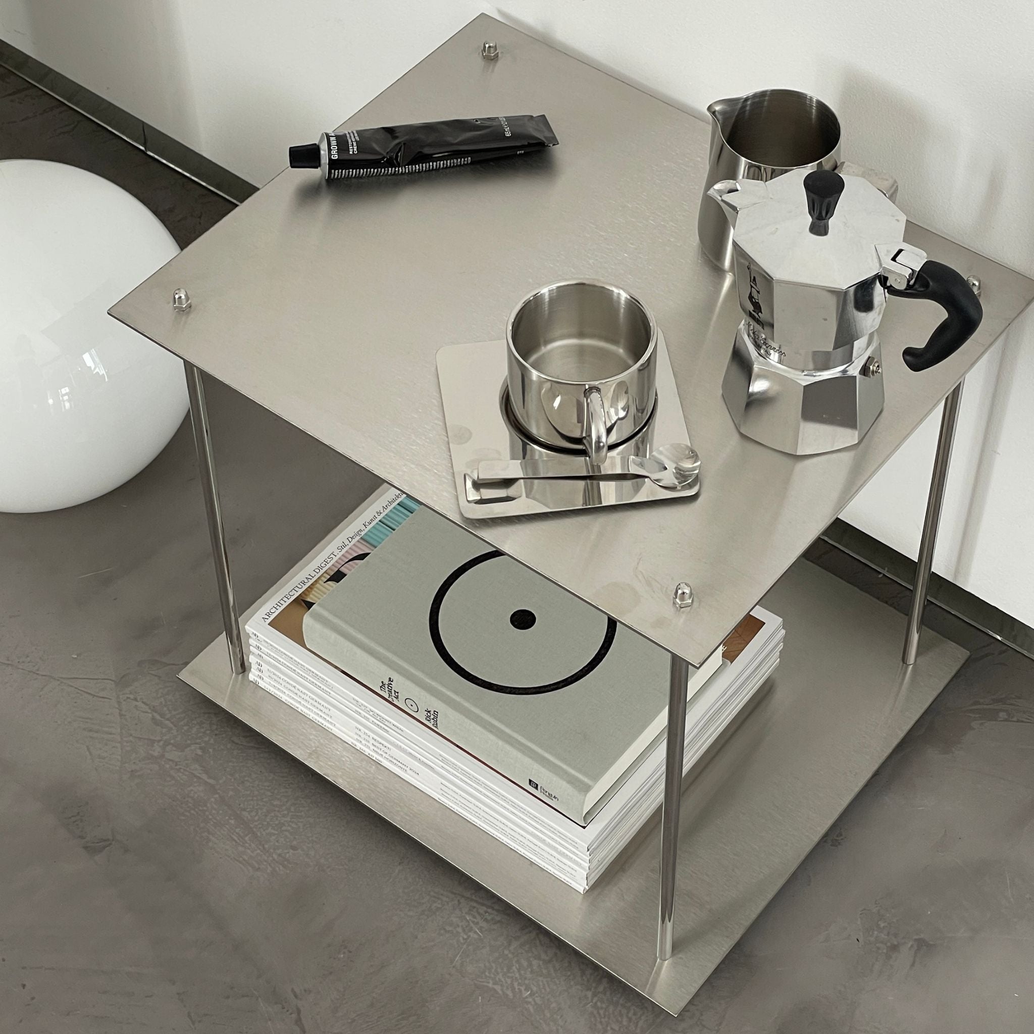 Minimalistisches Edelstahl-Regal mit Espressokanne, Tasse und Designmagazinen