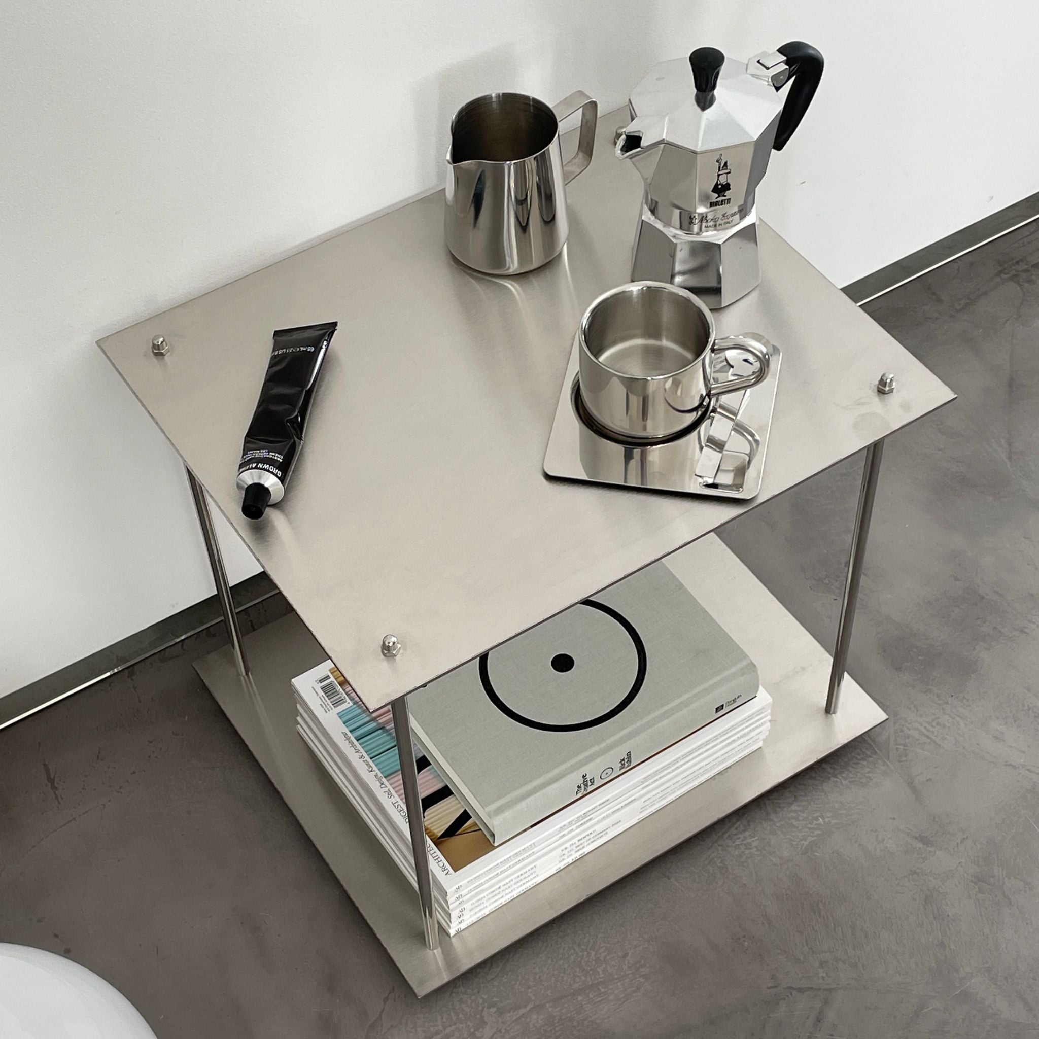 Modernes Edelstahl-Regal mit Espressokanne, Milchkännchen und Designmagazinen