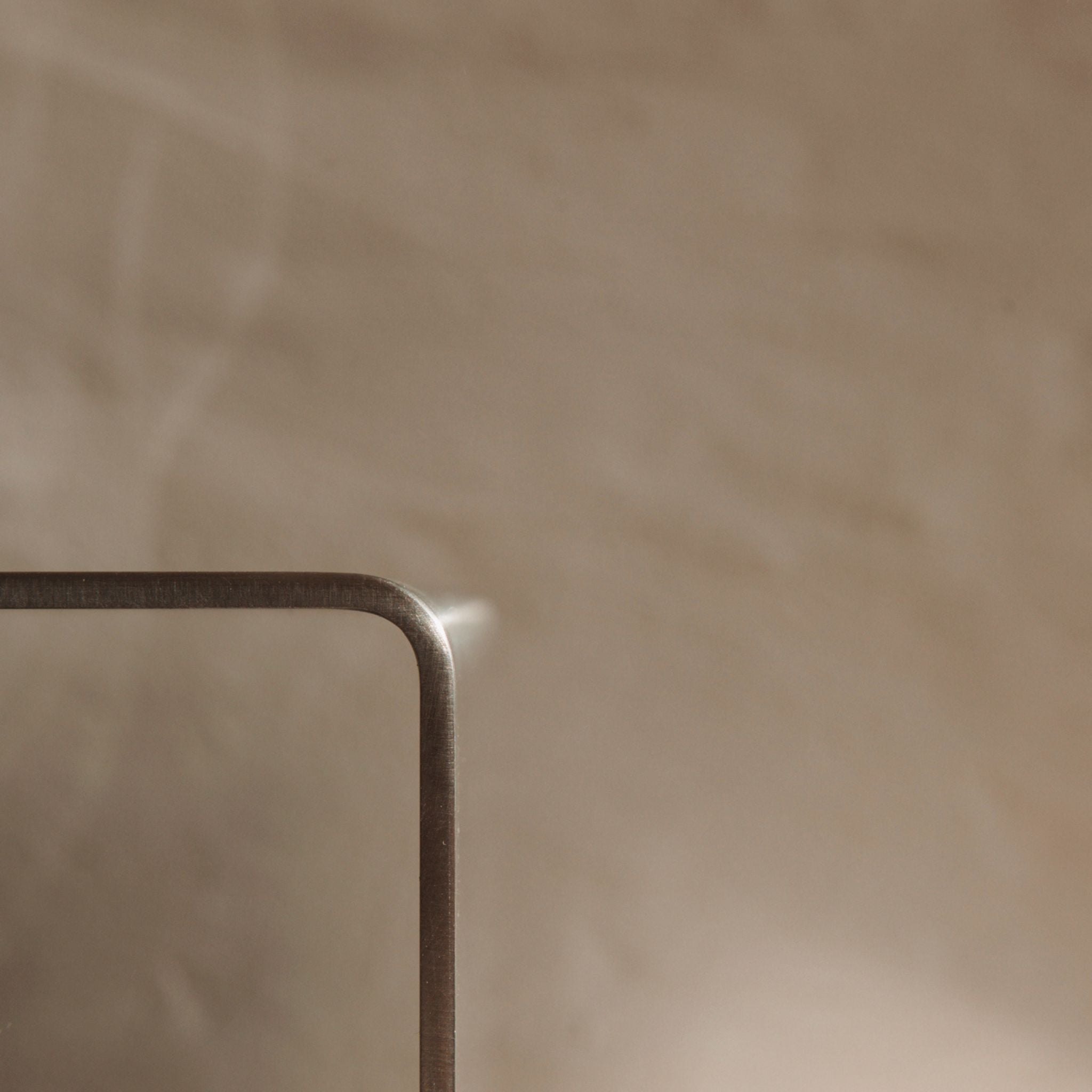 Detailaufnahme einer gebogenen Edelstahlkante mit sanfter Lichtreflexion