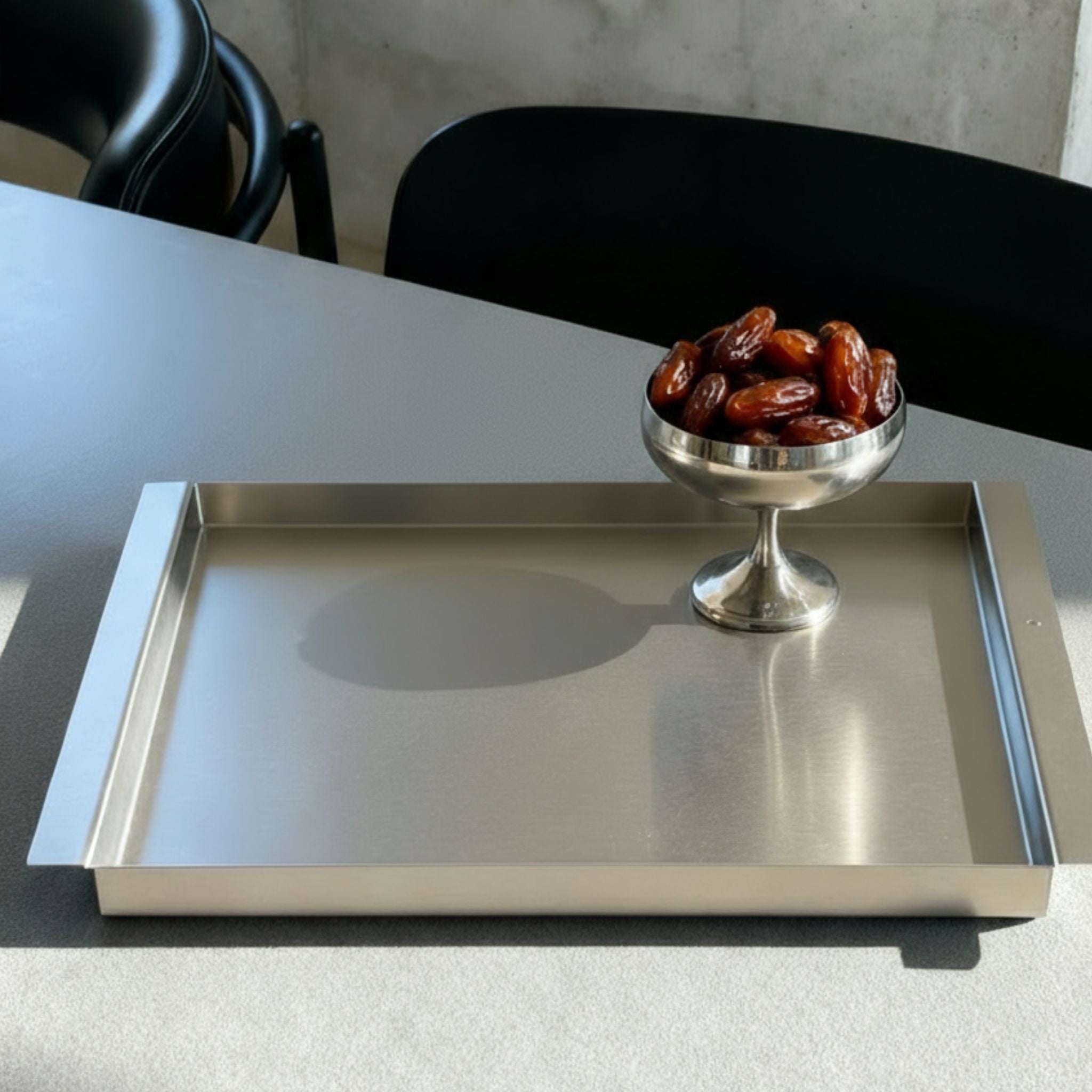 Edelstahl Tablett RAY mit Datteln auf modernem Esstisch im minimalistischen Interior Design von MO INTERIORS