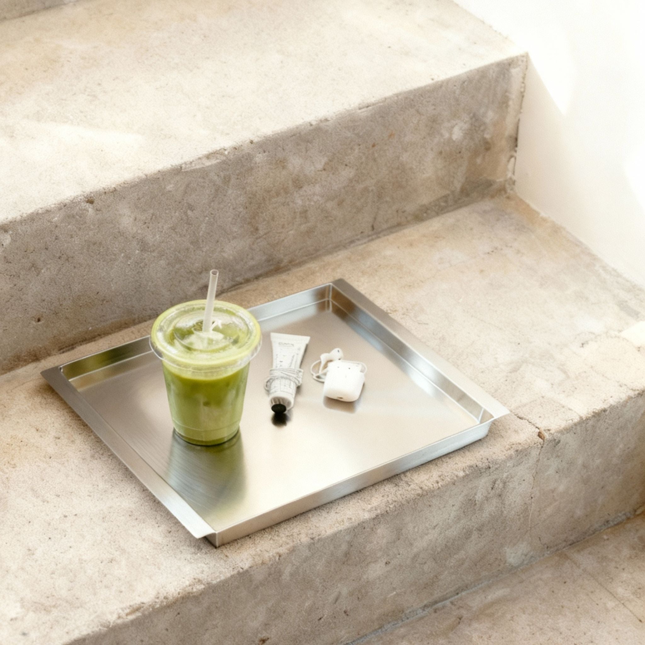 Edelstahl Tablett RAY mit Matcha Drink und Alltagsobjekten auf Betontreppe im minimalistischen Interior von MO INTERIORS
