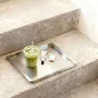 Edelstahl Tablett RAY mit Matcha Drink und Alltagsobjekten auf Betontreppe im minimalistischen Interior von MO INTERIORS