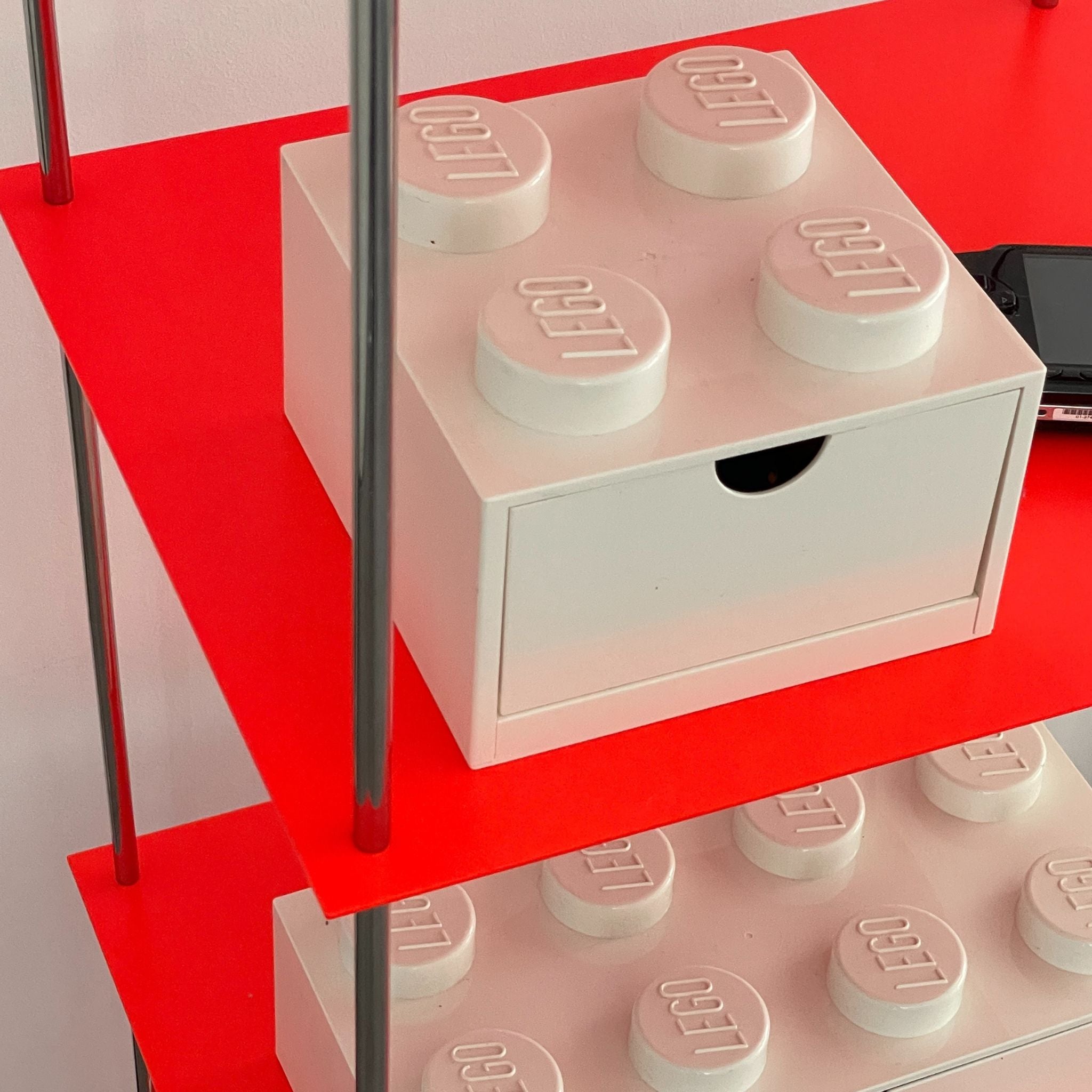 Nahaufnahme Regalboden in Leuchtrot mit weißer Lego-Schublade