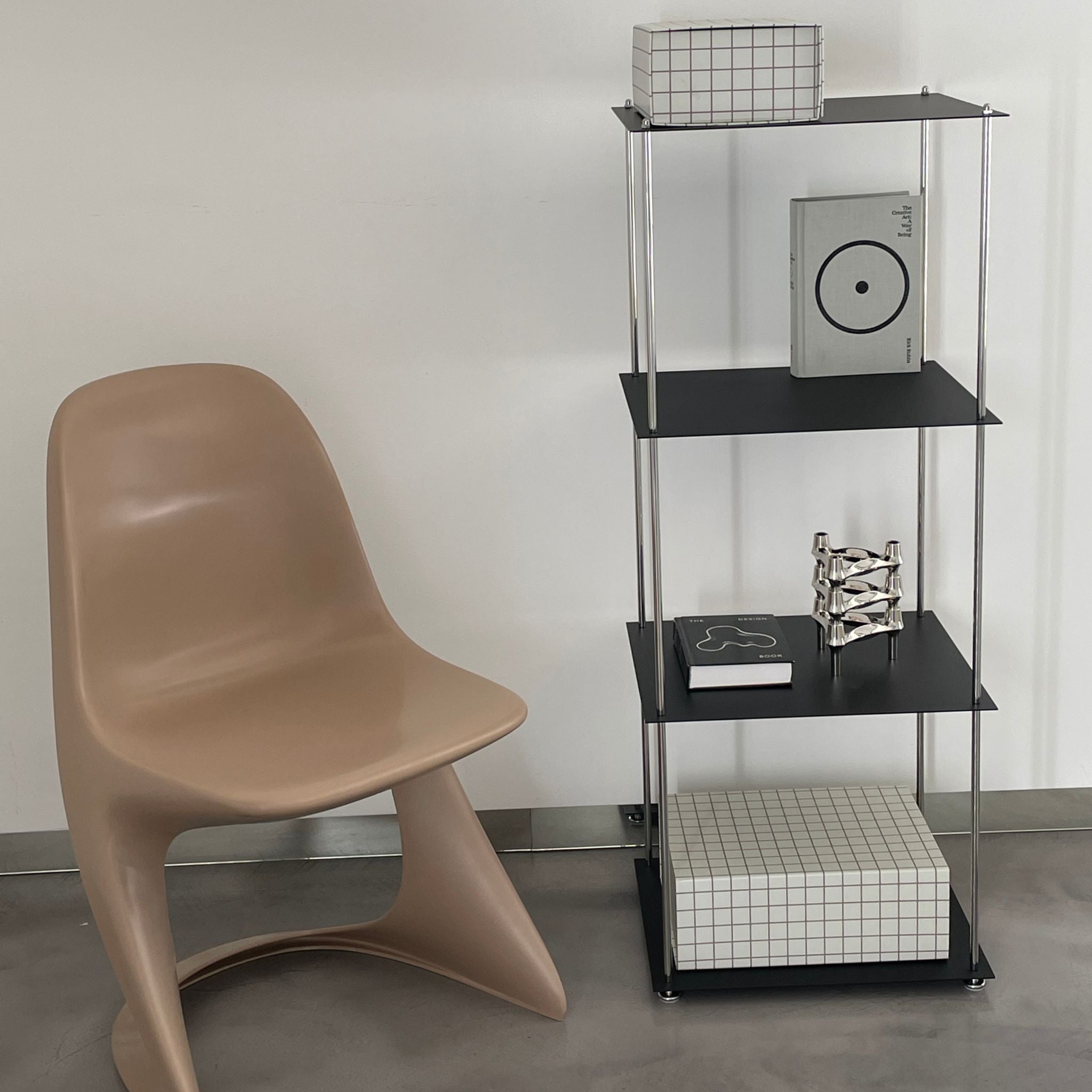 Modernes schwarzes Regal von MO INTERIORS mit Designobjekten und beigem Stuhl in puristischem Wohnraum