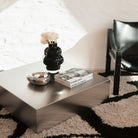 Moderner Couchtisch aus Edelstahl mit Dekoration in stilvollem Loft-Interieur