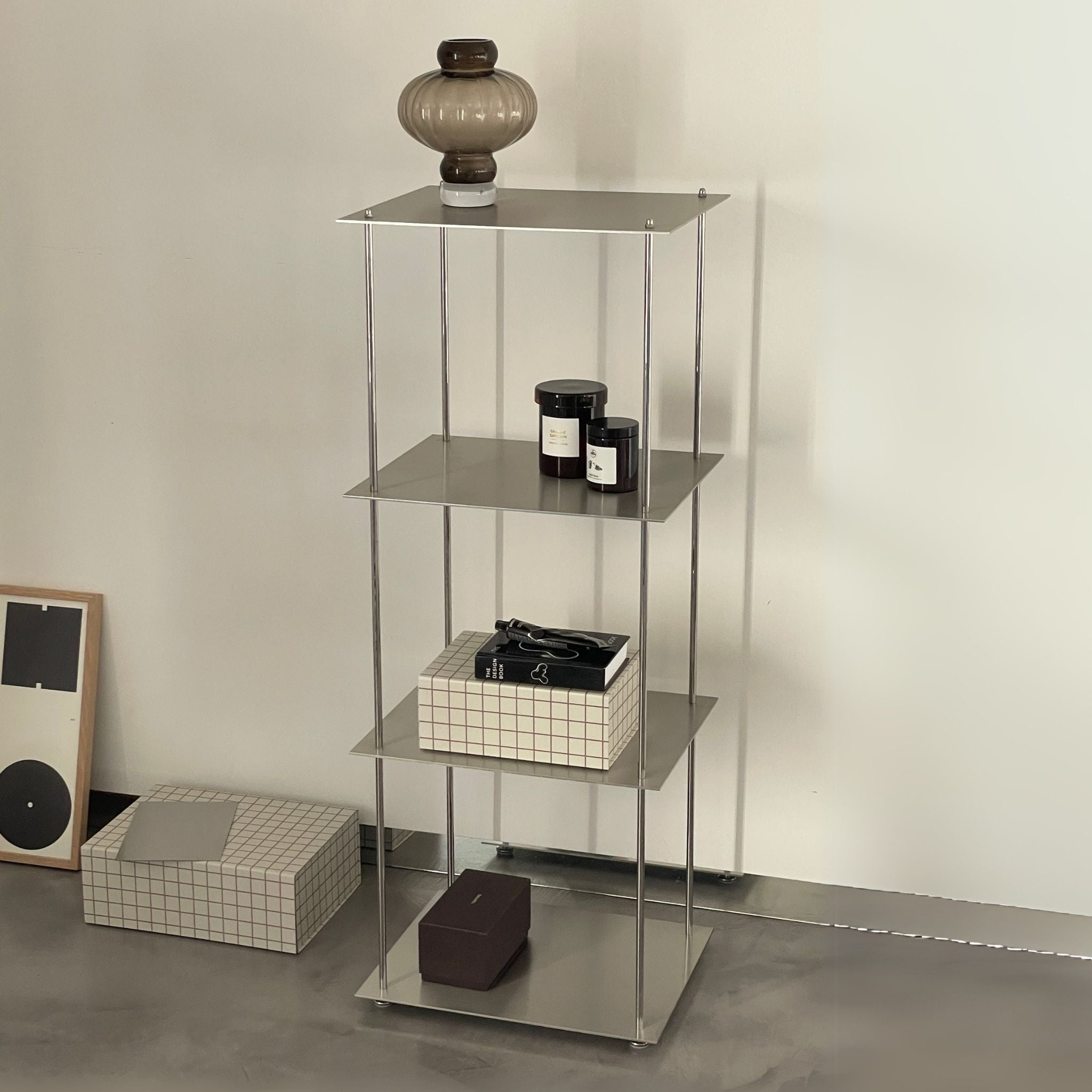 Modernes Edelstahl-Regalsystem mit Deko-Objekten und Glaslampe in minimalistischem Interior