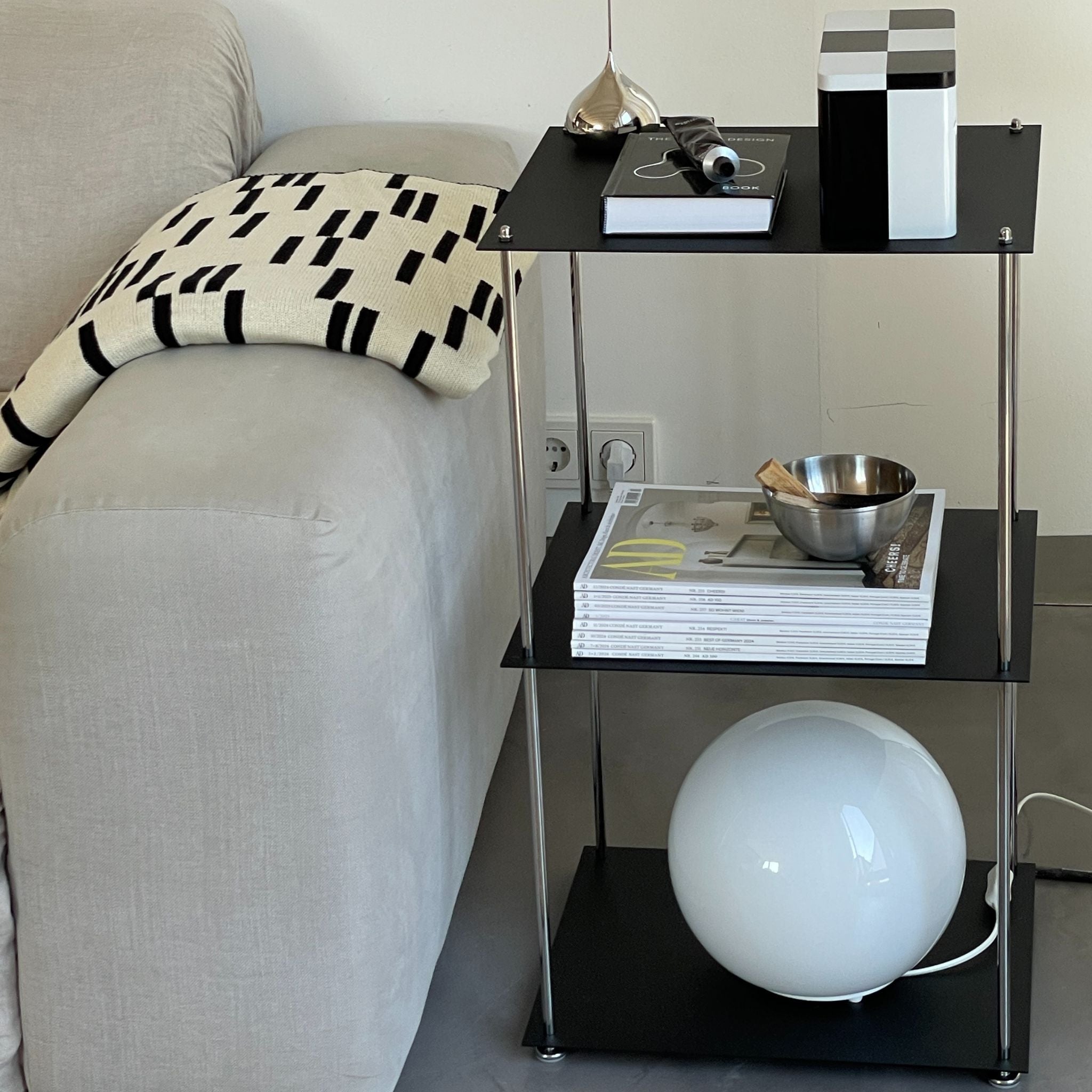 Schwarzes MODULUM Regal mit drei Ebenen, pulverbeschichtet und modern eingerichtet im Wohnzimmer