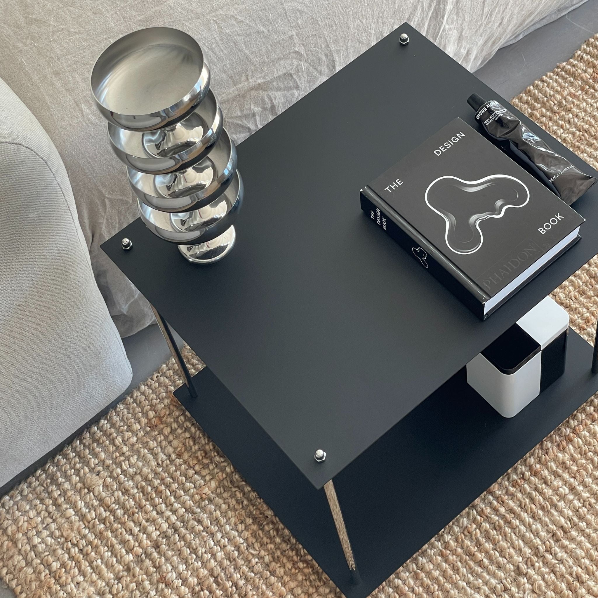 Detailansicht des MODULUM Beistelltischs in Schwarz mit Designobjekten – minimalistisches Möbelstück für stilvolle Räume