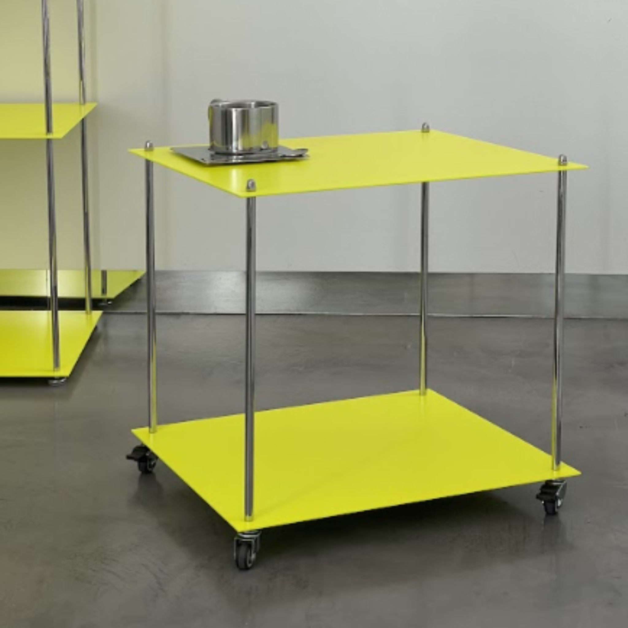 Leuchtgelbes Regalmodul Modulum mit Rollen und Edelstahlstreben, seitliche Perspektive auf grauem Betonboden