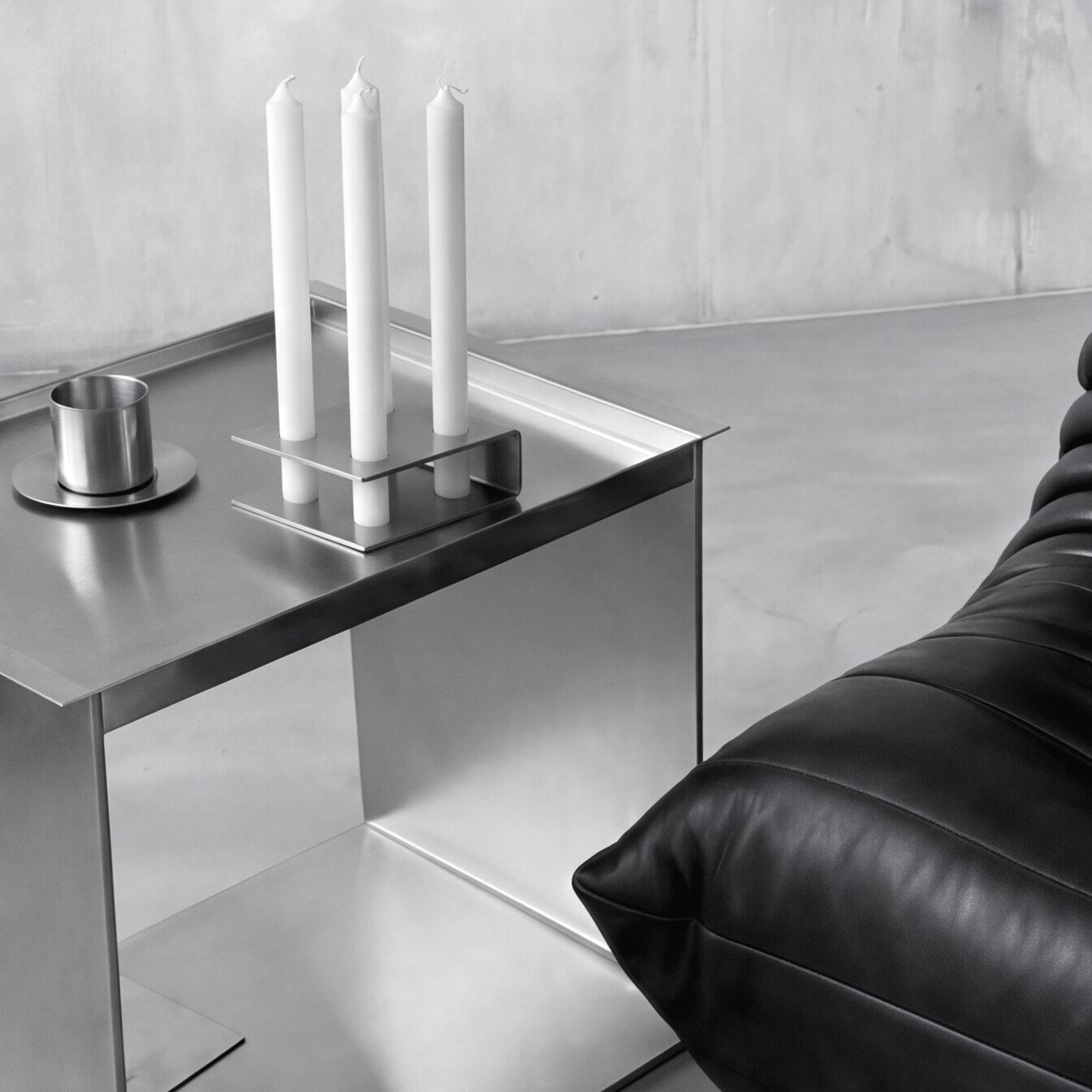 MO Objects: Object Holder mit Stabkerzen im Wohnraum, auf einem Edelstahl-Beistelltisch neben einem Ledersofa