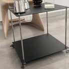 Moderner Servierwagen aus schwarzem Stahl mit Rollen im minimalistischen Interior neben Designstuhl und Kaffeegeschirr