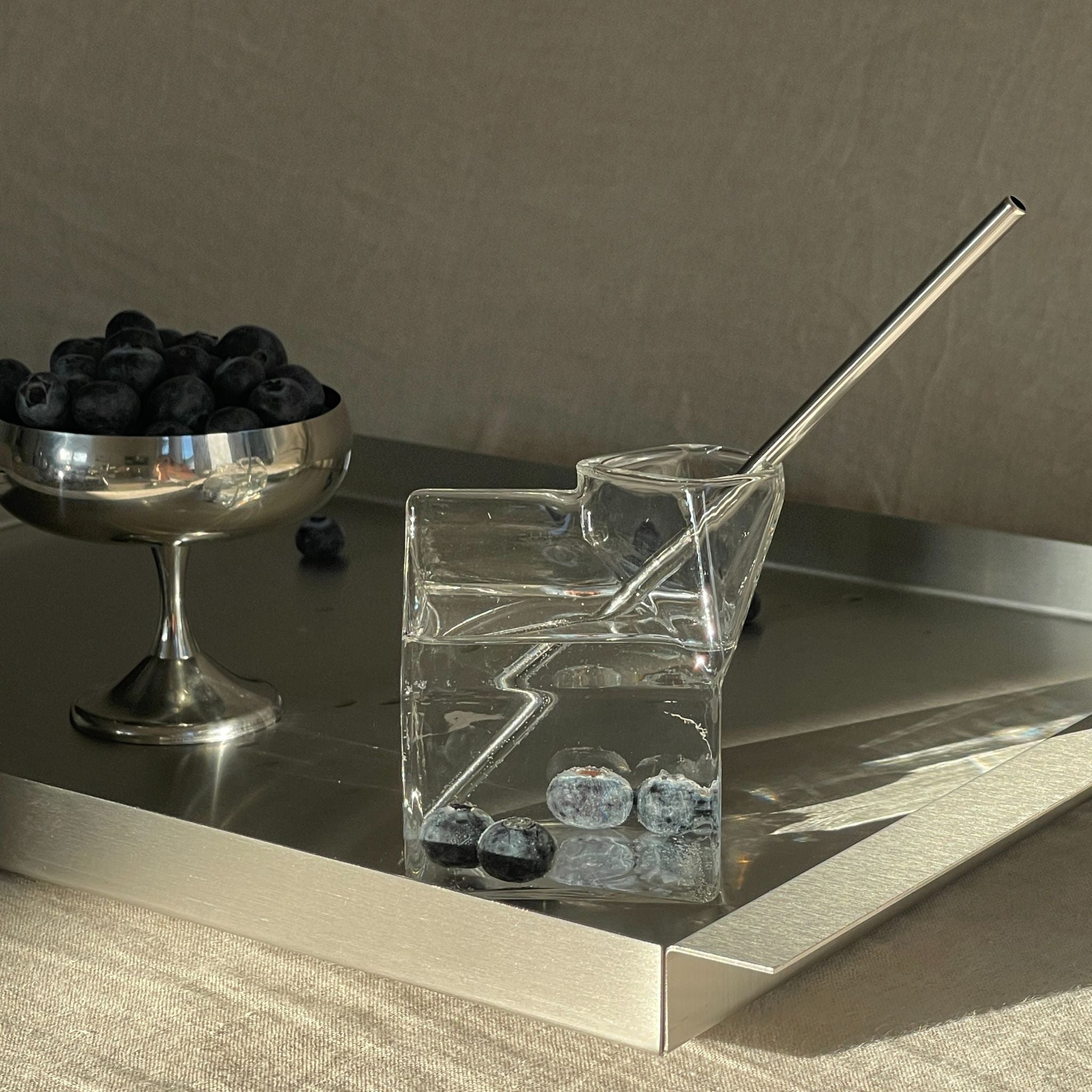 edelstahl tablett mit milchkarton glas und blaubeeren im morgenlicht